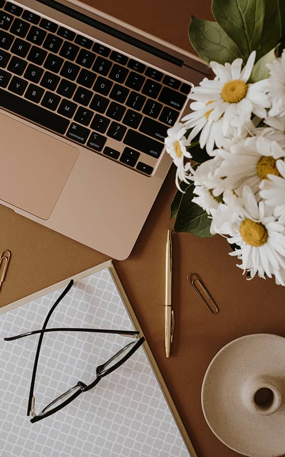 glasses, a laptop, and flowers on a table